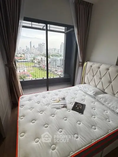 Cozy bedroom with city view from a high-rise apartment balcony.