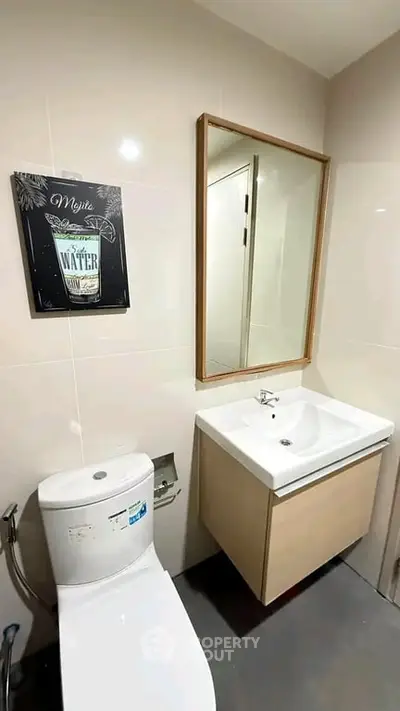 Modern bathroom with sleek fixtures and stylish wall art, featuring a compact sink and toilet.
