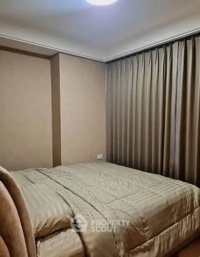 Cozy bedroom with elegant curtains and plush bedding in a modern apartment.