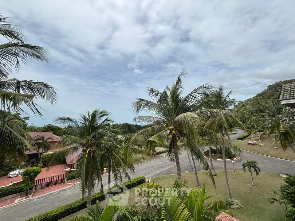 Stunning tropical view with palm trees and residential area under a clear sky.