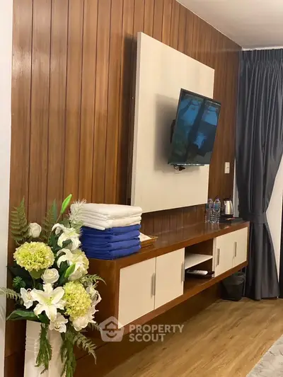 Stylish modern living room with wooden paneling and mounted TV, featuring elegant decor and cozy ambiance.