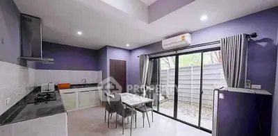 Modern kitchen with open layout, sleek appliances, and large sliding glass doors to outdoor area.