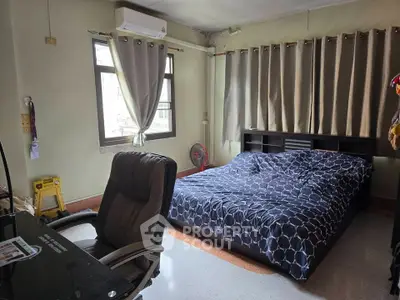 Spacious bedroom with modern decor and ample natural light, featuring a comfortable bed and work desk.
