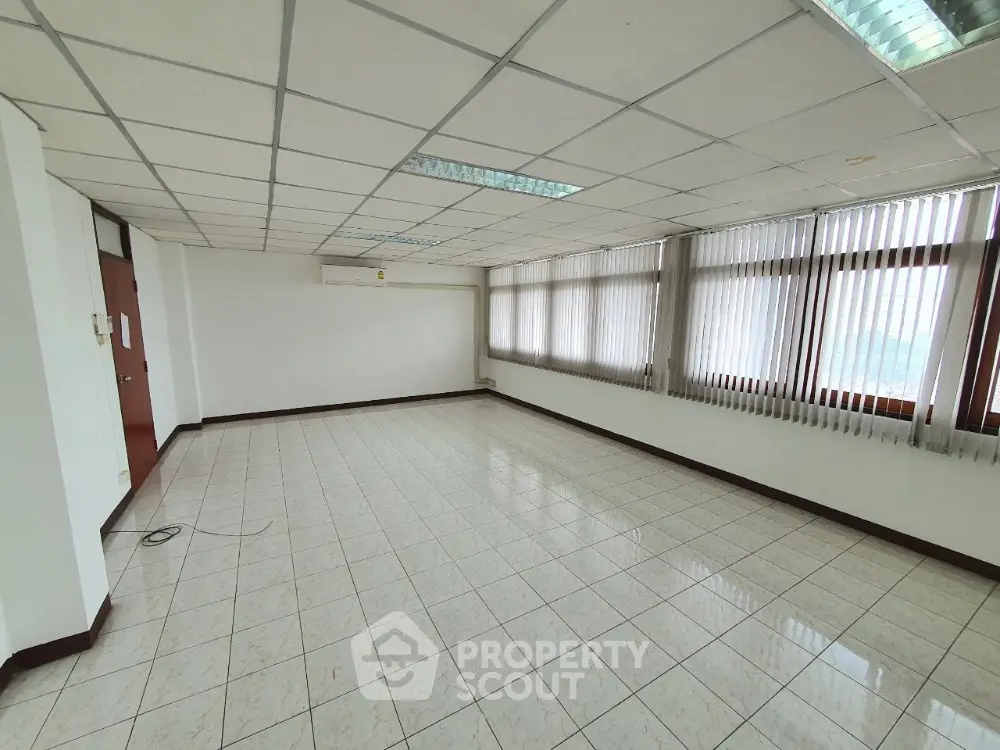 Spacious empty room with tiled flooring and large windows, perfect for office or studio setup.