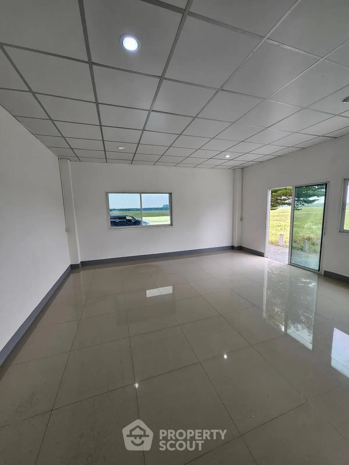 Spacious empty room with large windows and glossy tiled floor, ideal for customization.