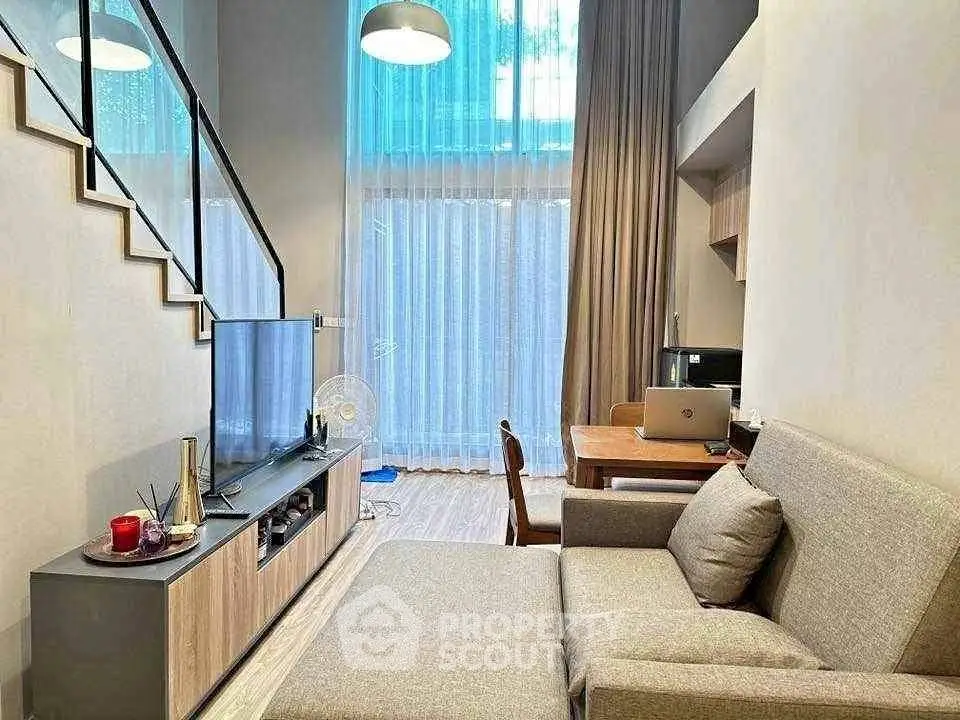 Modern living room with high ceiling and large window, featuring stylish furniture and a cozy atmosphere.