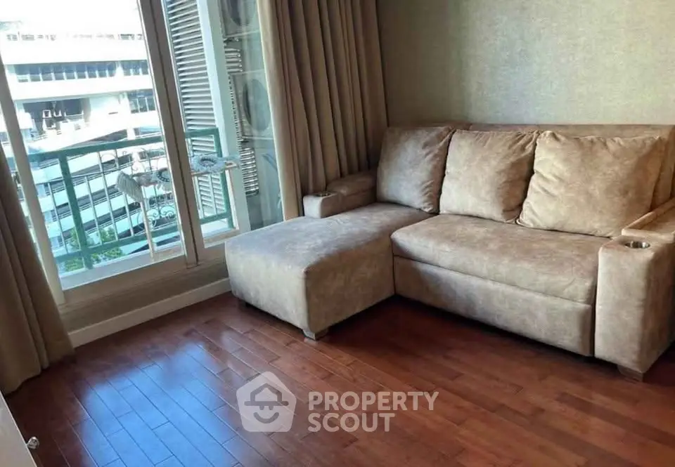 Cozy living room with plush sofa and wooden flooring, featuring a balcony view.