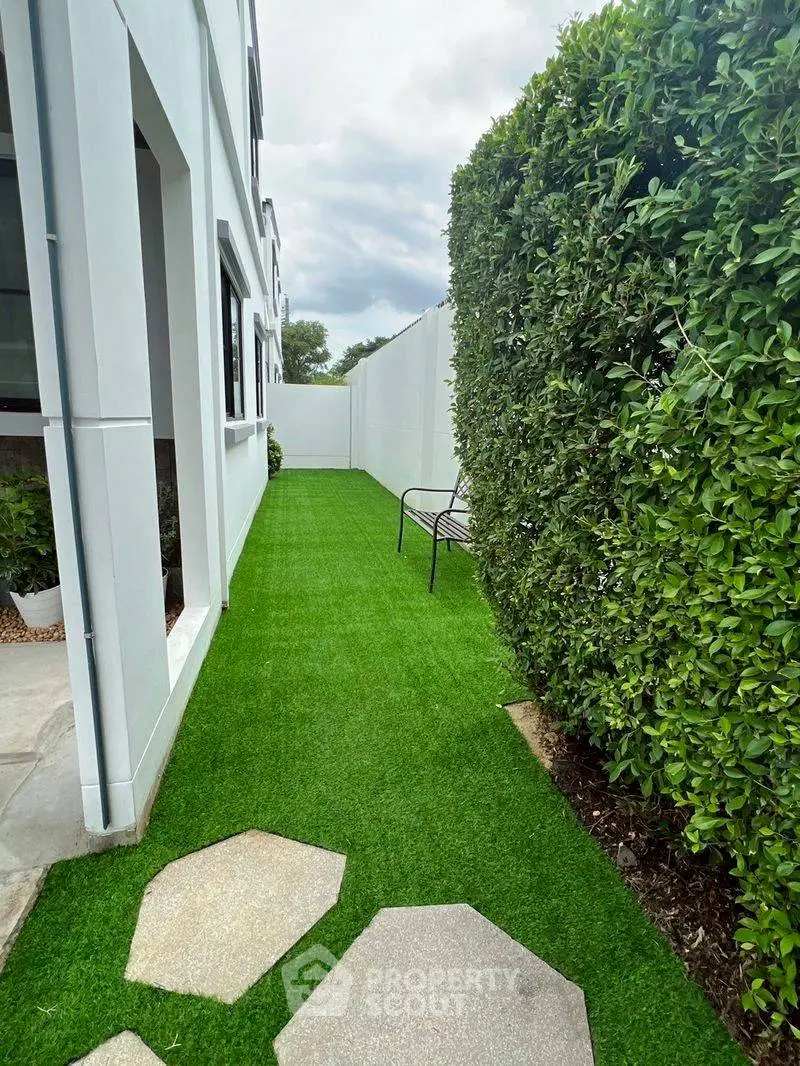 Charming side garden with lush greenery and modern pathway in a contemporary home setting.