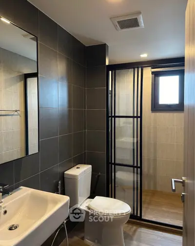 Modern bathroom with sleek black tiles and glass shower enclosure