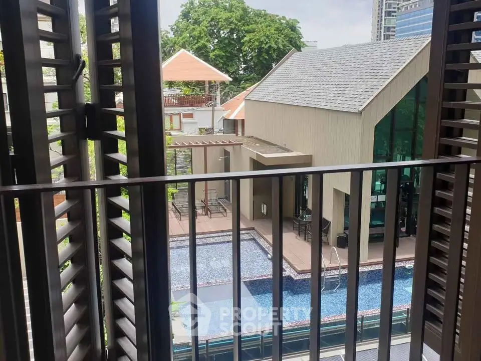 Chic urban apartment with balcony overlooking modern pool and lush greenery, perfect for relaxation and leisure.