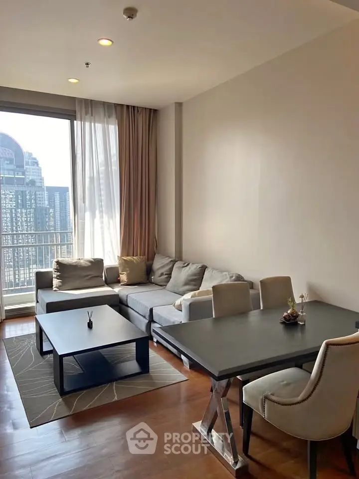 Modern living room with cozy seating and dining area, featuring large windows and stylish decor.