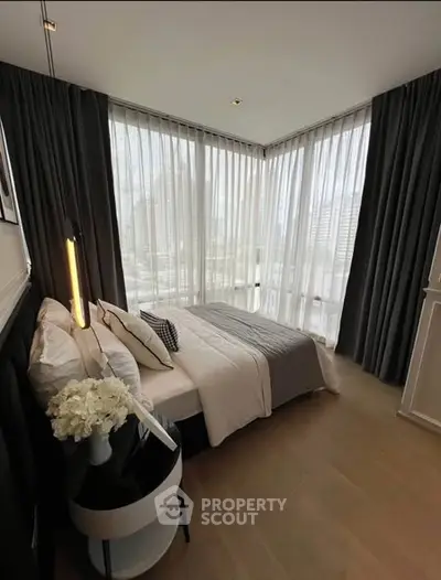 Luxurious corner bedroom with floor-to-ceiling windows and city view, featuring elegant decor and cozy ambiance.