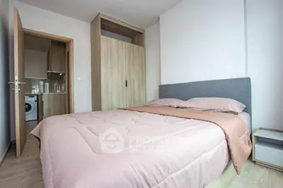 Modern bedroom with cozy bed and view into kitchen area, perfect for urban living.