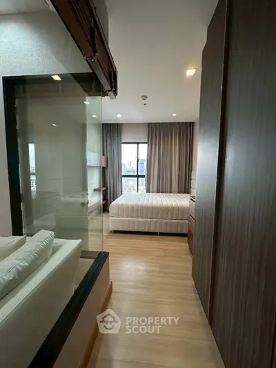 Modern bedroom with large window and city view, featuring sleek wooden furniture and cozy ambiance.