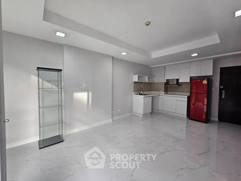 Spacious modern kitchen with sleek white cabinets and red fridge in a bright open layout.