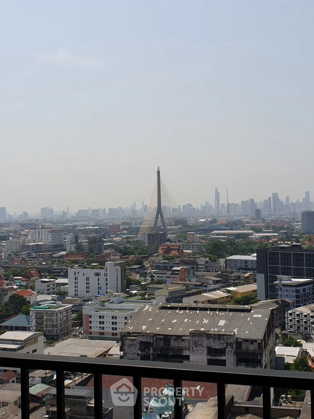 Stunning cityscape view from a high-rise balcony overlooking urban skyline and iconic bridge.