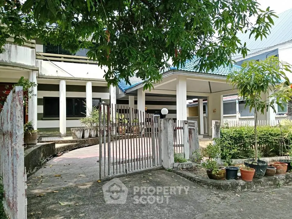 Charming suburban home with spacious front yard and gated entrance, surrounded by lush greenery.