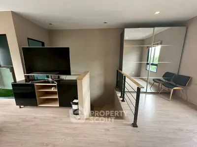 Modern living space with sleek TV stand and mirrored closet, featuring stylish chairs and staircase.