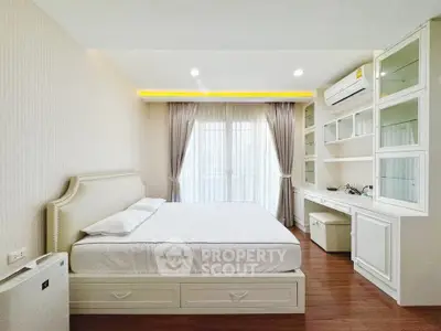 Spacious bedroom with elegant built-in storage and large window for natural light.