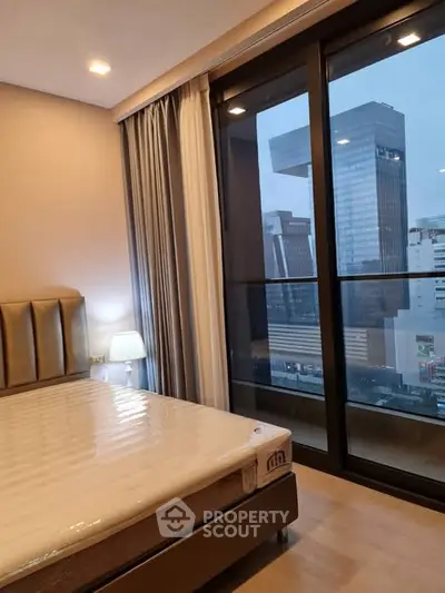 Modern bedroom with city view and large windows in high-rise apartment.