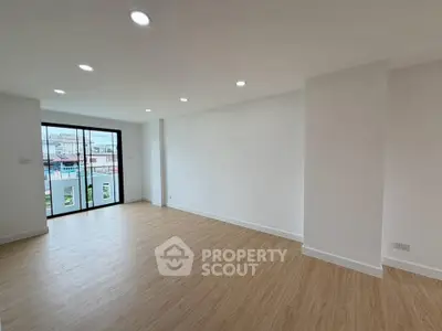 Spacious modern living room with wooden flooring and large windows offering natural light.