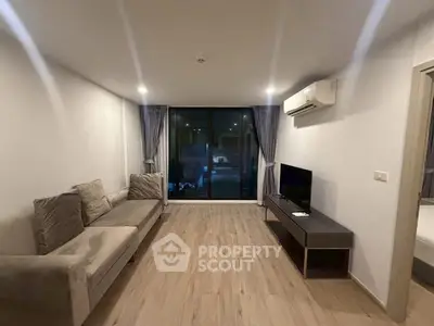 Modern living room with sleek design, featuring a comfortable sofa, flat-screen TV, and large windows for natural light.