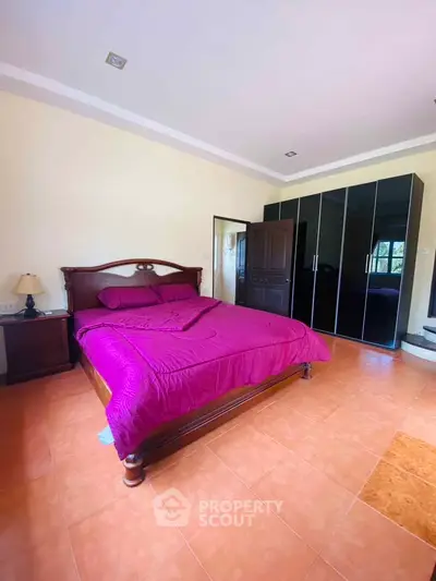 Spacious bedroom with elegant wooden bed and large wardrobe in a cozy home.