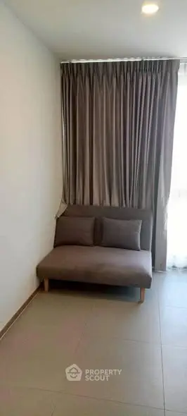 Cozy minimalist living room with a stylish gray sofa and elegant floor-to-ceiling curtains.