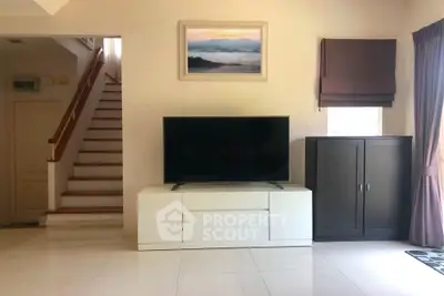 Spacious living room with modern TV setup and elegant staircase