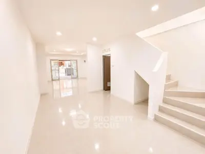 Spacious modern living room with sleek staircase and glossy tiled floors