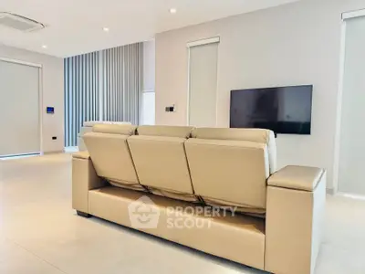 Modern living room with sleek beige sofa and wall-mounted TV in a minimalist design.