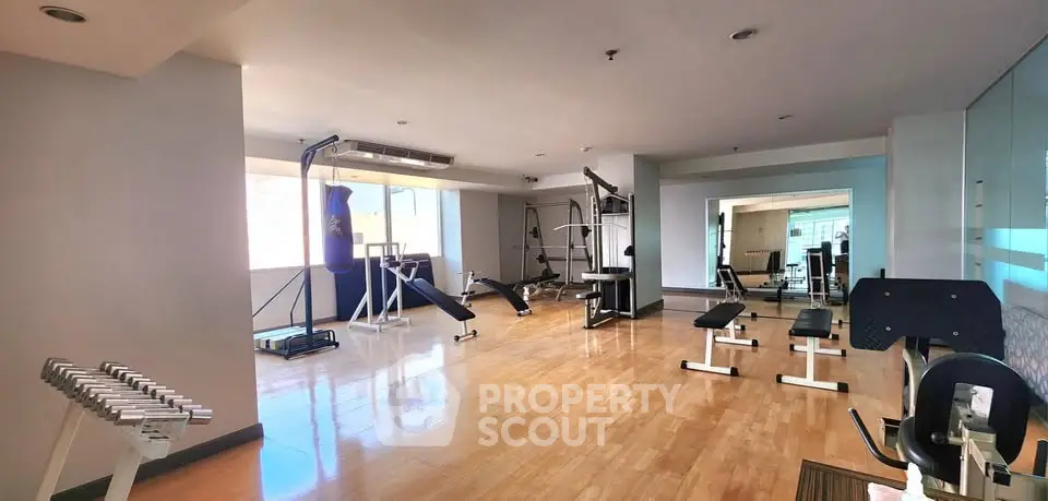 Spacious gym with modern equipment and wooden flooring in a residential building.