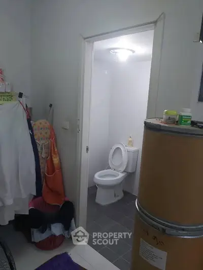 Compact bathroom with open door view, featuring basic amenities and tiled flooring.