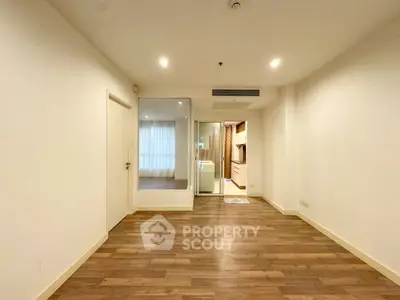 Spacious empty room with wooden flooring and modern lighting, ideal for customization.