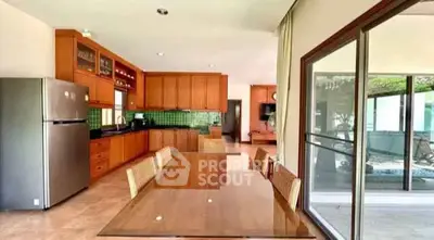Spacious kitchen with wooden cabinets and dining area, featuring a large glass sliding door.