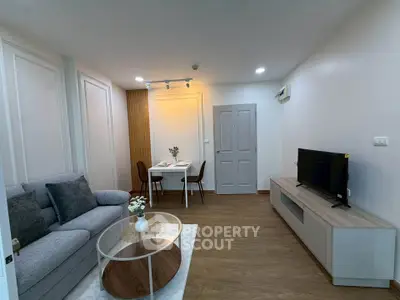 Modern living room with cozy seating and dining area, featuring stylish decor and a flat-screen TV.