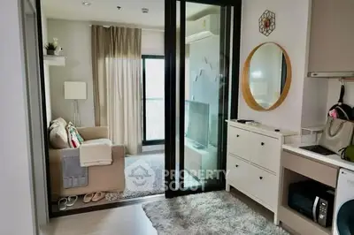 Modern living room with cozy decor and sliding glass doors leading to a balcony, featuring a compact kitchen area.