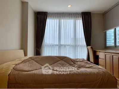 Spacious bedroom with large window and elegant curtains, featuring a cozy bed and a functional desk area.