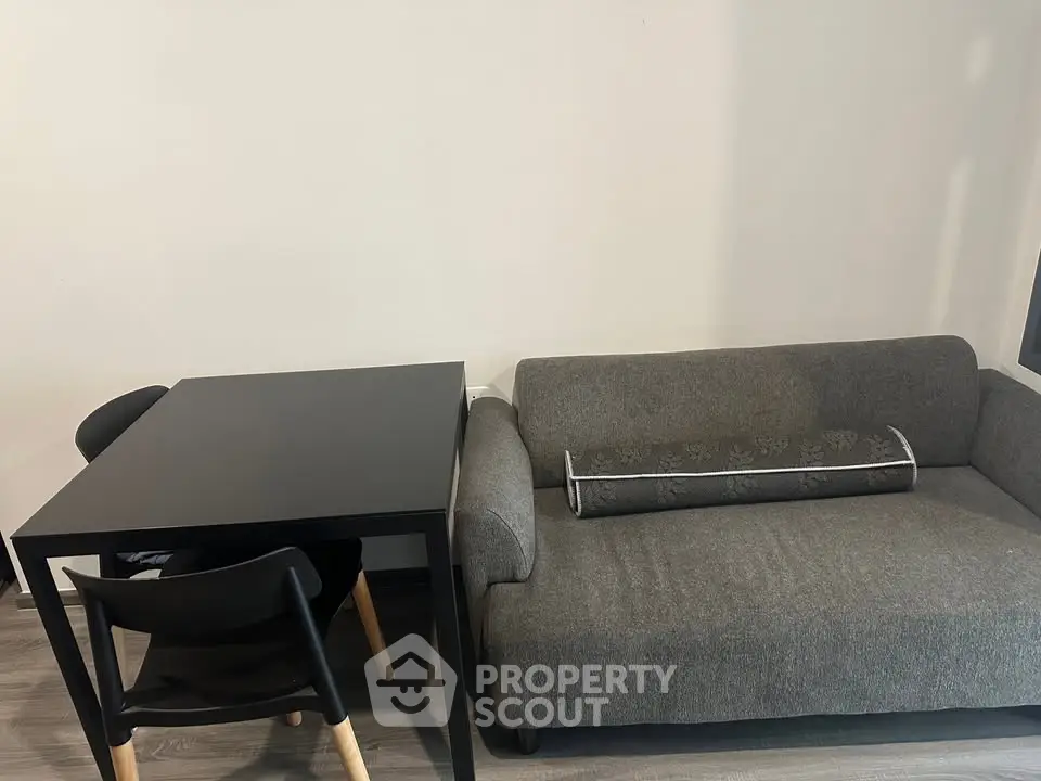 Modern living room with sleek gray sofa and minimalist black dining table.