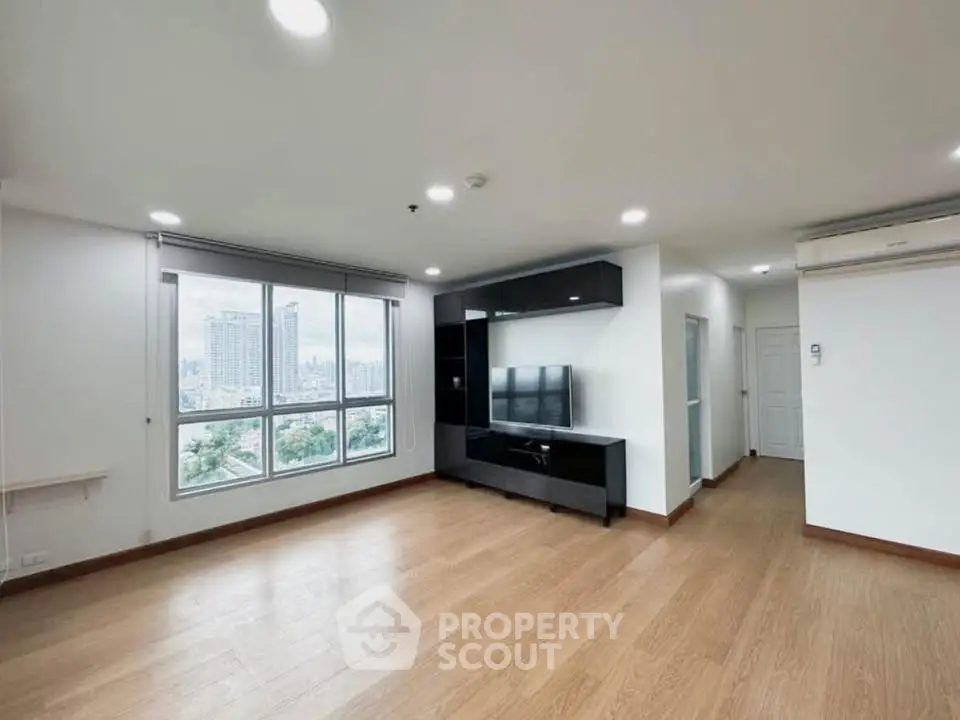 Spacious modern living room with city view and sleek entertainment unit.