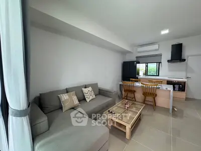 Modern living room with cozy gray sofa and stylish kitchen area in open layout apartment.