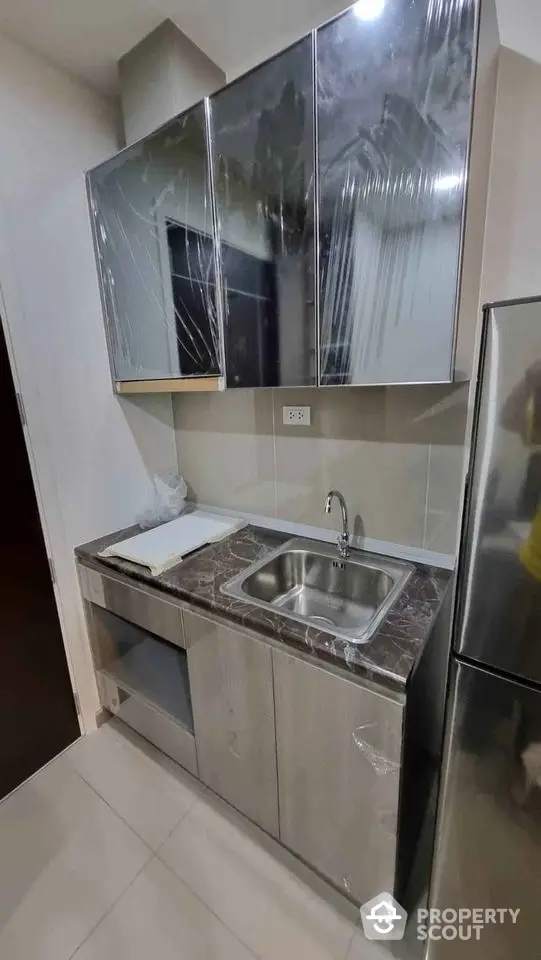 Modern kitchen with sleek cabinetry and stainless steel sink in compact layout.