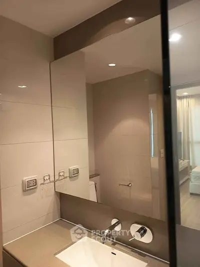 Modern bathroom with sleek fixtures and large mirror in a contemporary apartment.