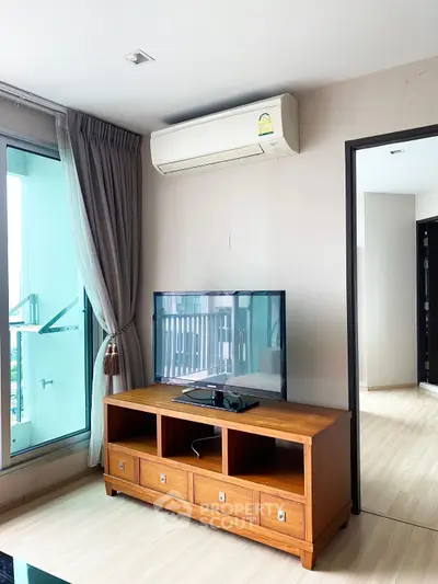 Modern living room with wooden TV stand and air conditioning, featuring a large window with city view.