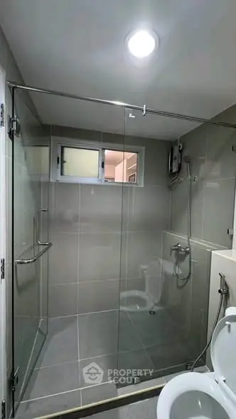 Modern bathroom with glass shower enclosure and sleek gray tiles