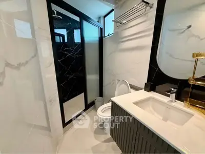 Modern bathroom with sleek design, featuring a glass shower enclosure and elegant fixtures.