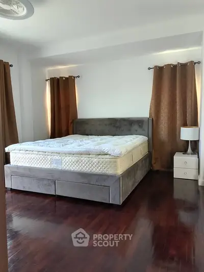Spacious bedroom with elegant bed and rich wooden flooring, perfect for relaxation.