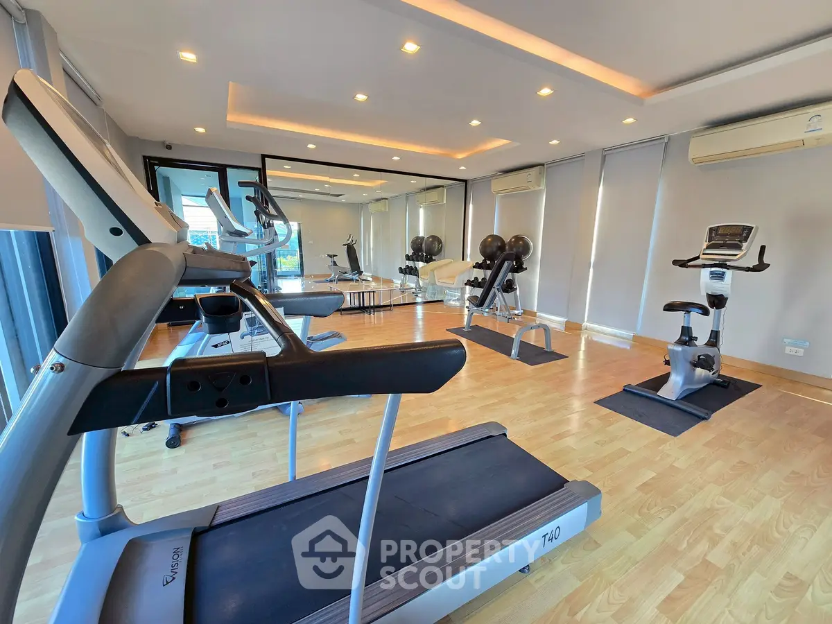 Modern gym with state-of-the-art equipment and mirrored walls in a luxury building.