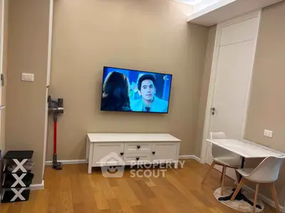 Cozy living room with mounted TV and dining area in modern apartment.