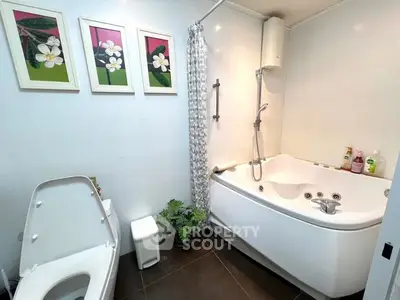 Spacious modern bathroom with a large jacuzzi tub, separate shower area, and elegant dark floor tiles, complemented by vibrant floral wall art.